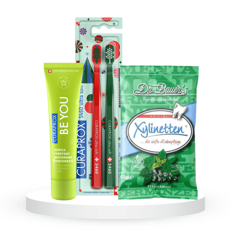 Balinantis komplektas: "Curaprox Be you" balinanti dantų pasta (60 ml), "Curaprox Chistmas 5460" dantų šepetėliai (2 vnt.) ir "Dr. Bauer's Xylinetten" ksilitolio pastilės (30 vnt.)